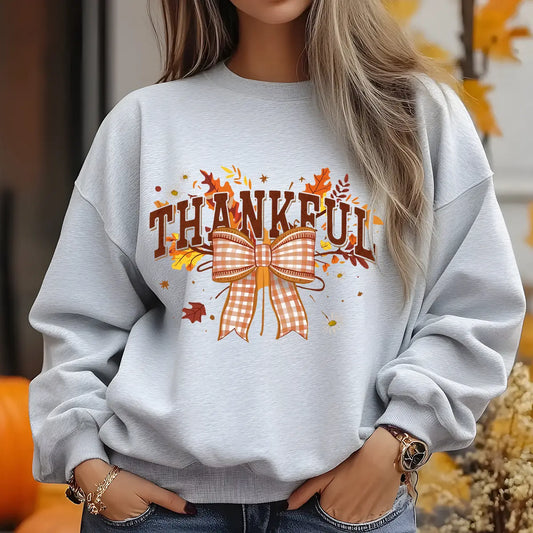 Grey sweatshirt with “Thankful” text, fall leaves, and gingham bow DTF transfer.