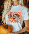 White t-shirt with “Thankful” checkered orange DTF transfer design featuring fall leaves and bow, perfect for Thanksgiving and autumn-themed apparel.