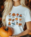 White t-shirt with colorful fall-themed doodles and words like pumpkins, bonfires, coffee, and cozy sweater, perfect for autumn-inspired custom shirts.