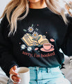 Black sweatshirt with “Sorry, I’m Booked” DTF transfer design featuring an open book with daisies, coffee cup, and reading glasses for cozy reader style.