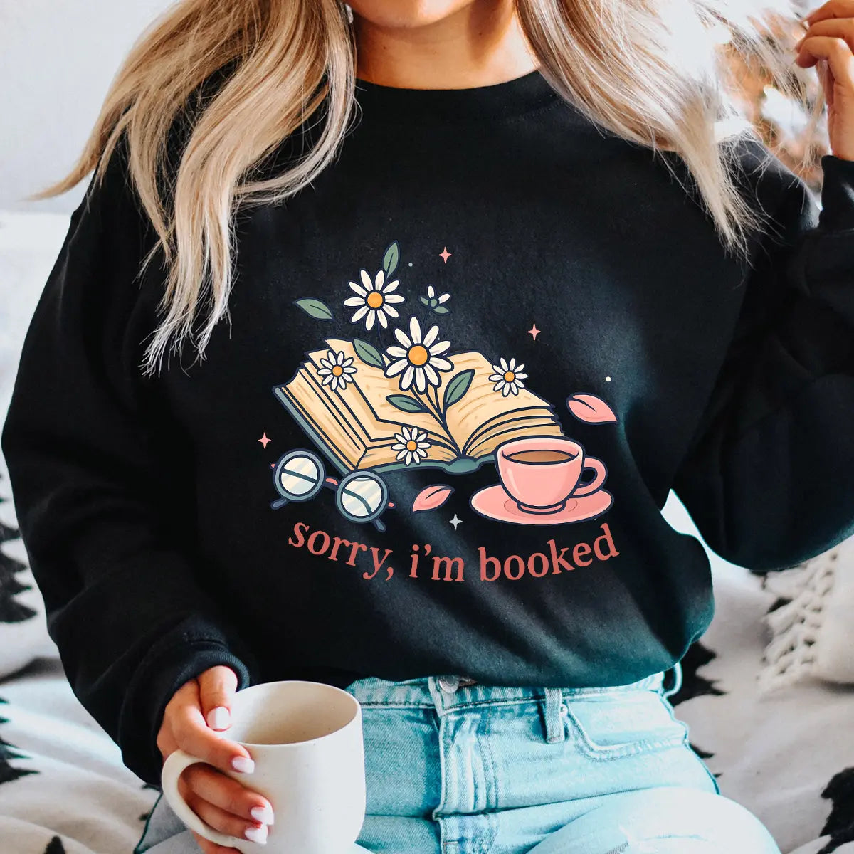 Black sweatshirt with “Sorry, I’m Booked” DTF transfer design featuring an open book with daisies, coffee cup, and reading glasses for cozy reader style.