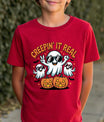 Red t-shirt with Halloween design featuring three cartoon ghosts in sunglasses, jack-o’-lantern pumpkins, bats, stars, and text “Creepin’ It Real.”