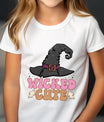 White t-shirt with Halloween design featuring a black witch hat, small ghosts, and text “Wicked Cute” in pink and orange retro lettering, perfect for kids’ spooky apparel.