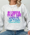 Gray sweatshirt with bold purple-to-blue gradient text reading “Be Careful. I’m Not Sure Which Me I Am Today. You Have Been Warned.” DTF transfer design for funny mood-inspired apparel.