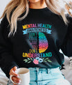 Black sweatshirt with rainbow brain graphic and text “Mental Health Awareness – Don’t Judge What You Don’t Understand” DTF transfer design, accented with flowers, for awareness apparel.