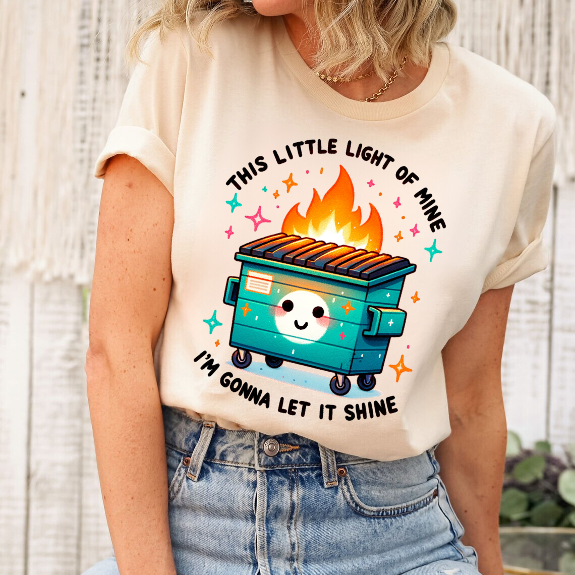 Cream t-shirt with 'This Little Light of Mine' DTF transfer, depicting a colorful dumpster fire with cheerful decorations