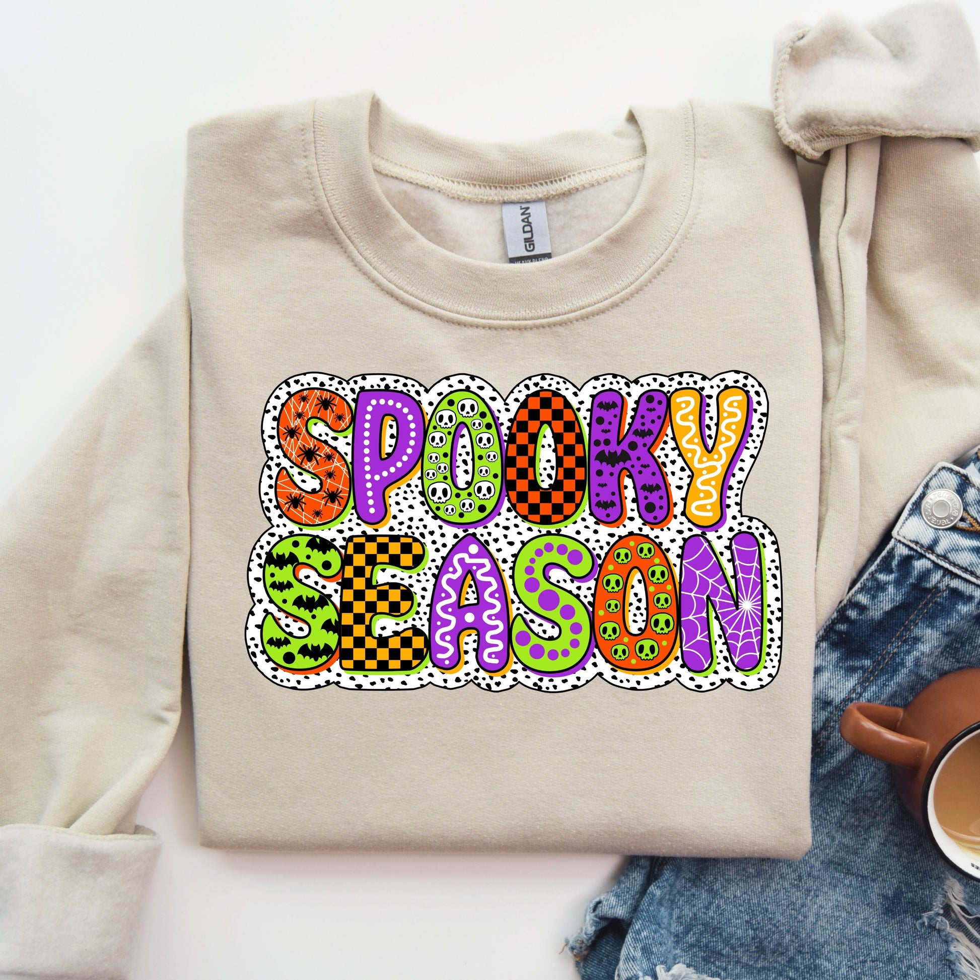 Beige sweatshirt with 'Spooky Season' DTF transfer in colorful, Halloween-themed patterns