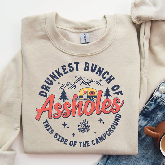 Beige sweatshirt with 'Drunkest Bunch of Assholes' campground-themed DTF transfer in a rustic design