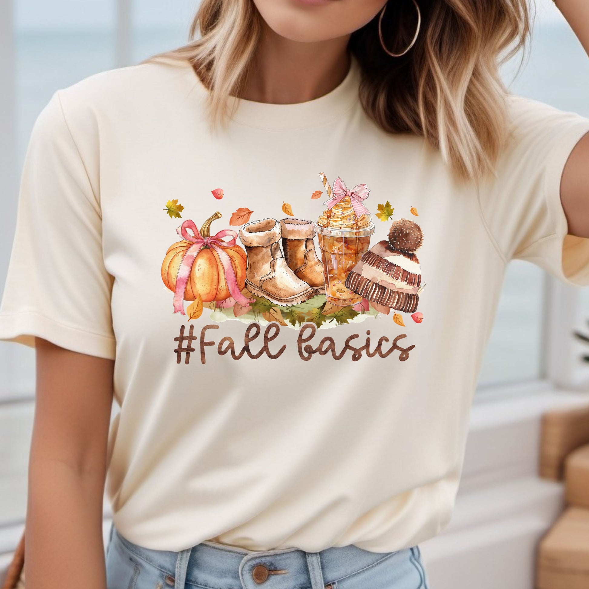 Illustrated 'Fall Basics' DTF transfer on a cream t-shirt with autumn-themed accessories