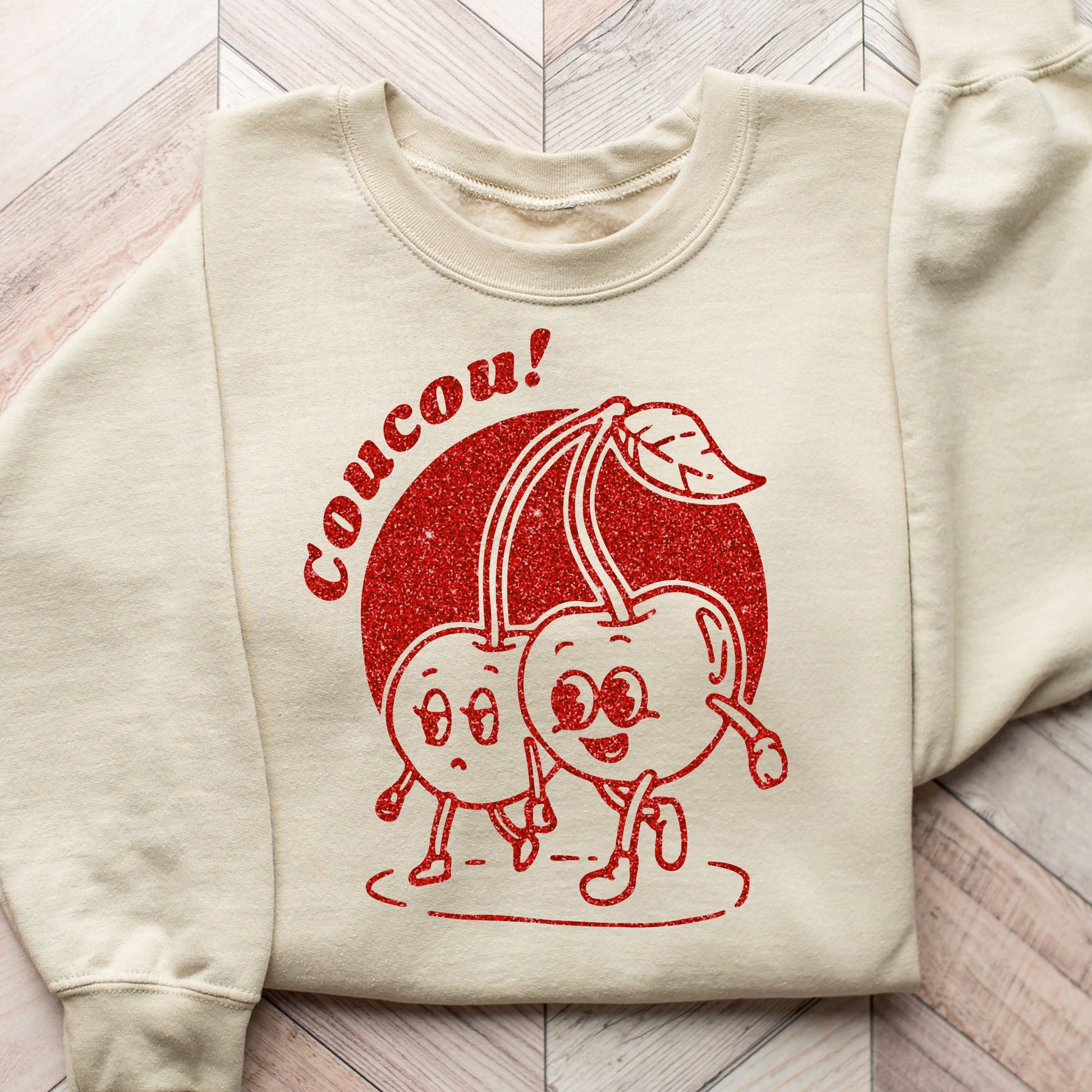 Whimsical Coucou Cherry duo DTF transfer on a beige sweatshirt, perfect for casual wear