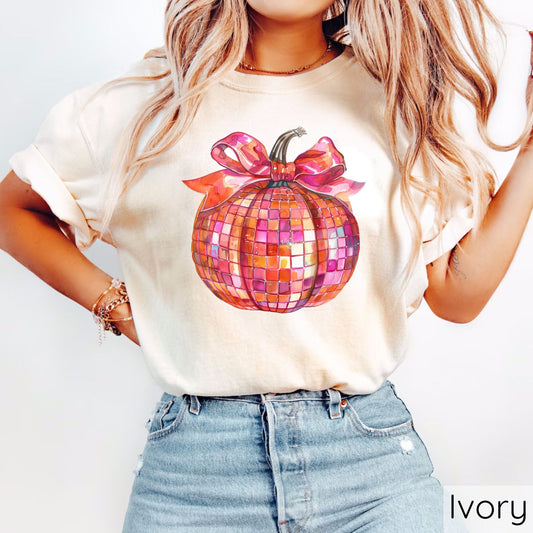 Colorful disco ball pumpkin with a bow on an ivory t-shirt.