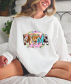 Smiling woman wearing a white sweatshirt featuring a Highland Cow MAMA rustic-style DTF transfer with floral and Western accents.