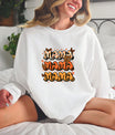 Smiling woman wearing a white sweatshirt with a boho butterfly MAMA DTF Transfer, featuring retro fonts, butterflies, and warm earthy tones.