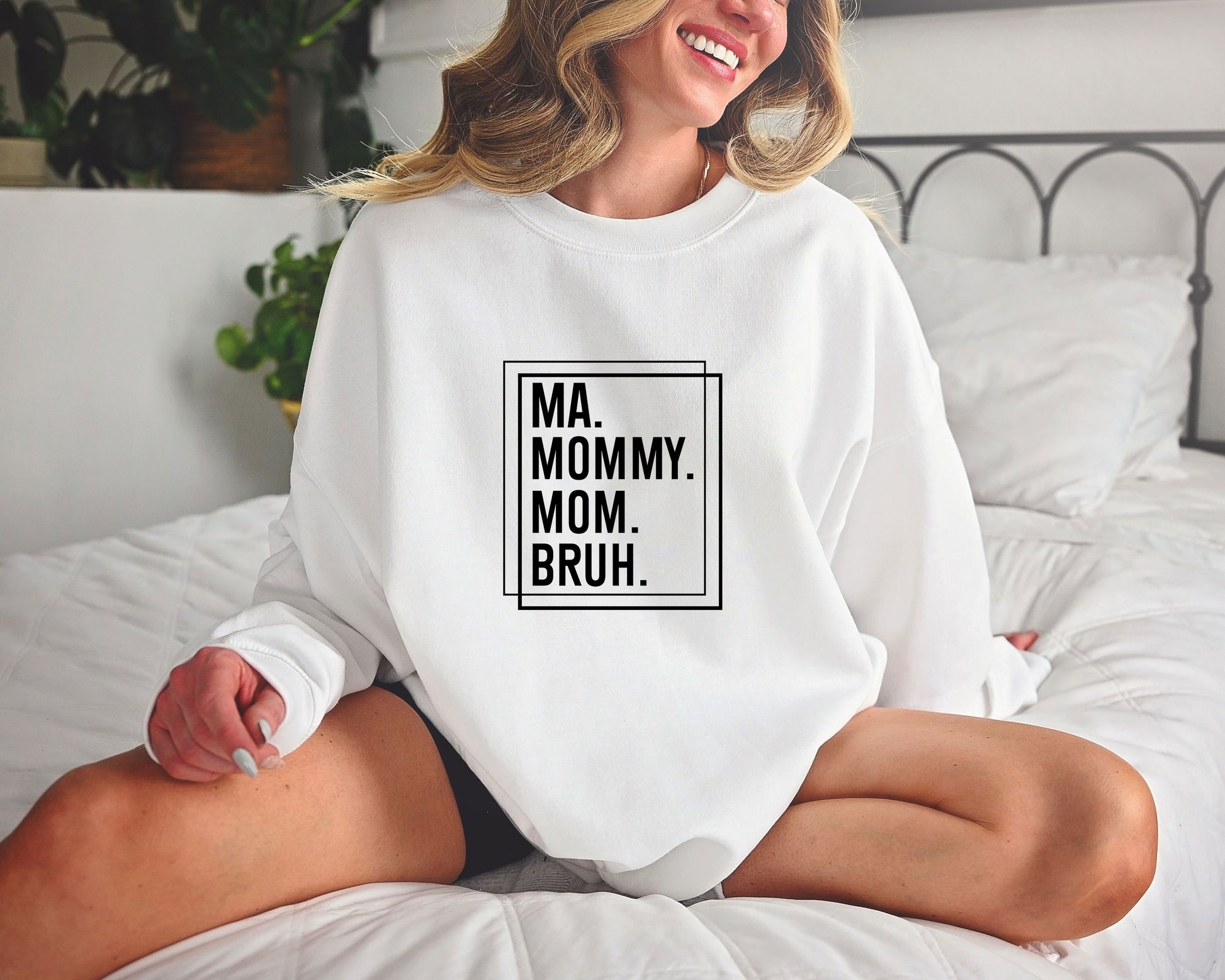 Smiling woman wearing a white sweatshirt with a black minimalist Ma. Mommy. Mom. Bruh. DTF Transfer, expressing the stages of motherhood.