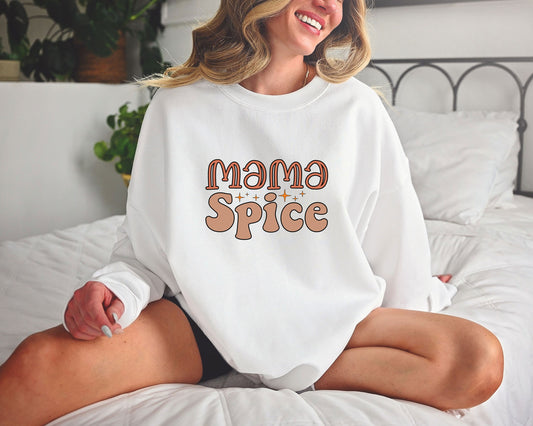 A woman wearing a white sweatshirt with a Mama Spice DTF Transfer, featuring a retro-style font with earthy tones and sparkling accents.