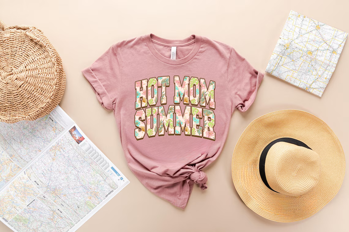 Hot Mom Summer ready-to-press DTF transfer design on a pink shirt with tropical patterned text, surrounded by maps and a straw hat.