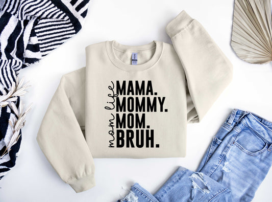 Beige sweatshirt featuring bold black text "MAMA. MOMMY. MOM. BRUH." with "mom life" written vertically, perfect for a fun Mother’s Day look.