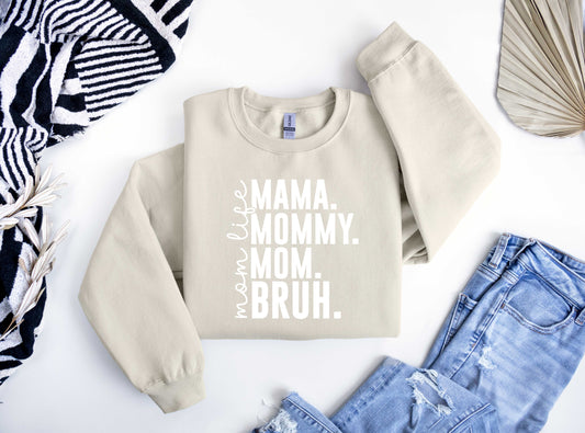 Beige sweatshirt featuring bold white text "MAMA. MOMMY. MOM. BRUH." with "mom life" written vertically, perfect for a fun Mother’s Day look.