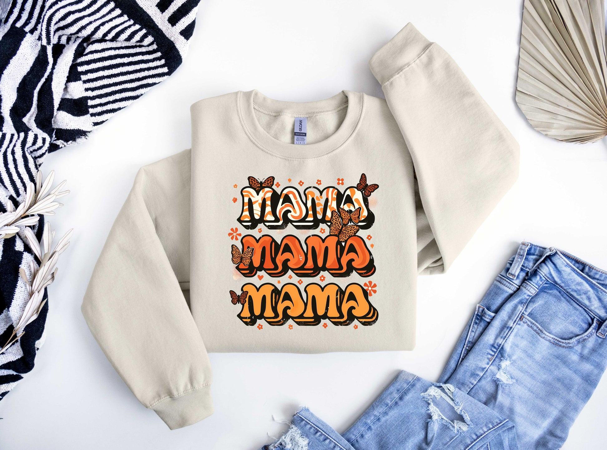 Beige sweatshirt featuring a retro "MAMA" design with orange tones, butterflies, and floral accents, perfect for Mother’s Day.