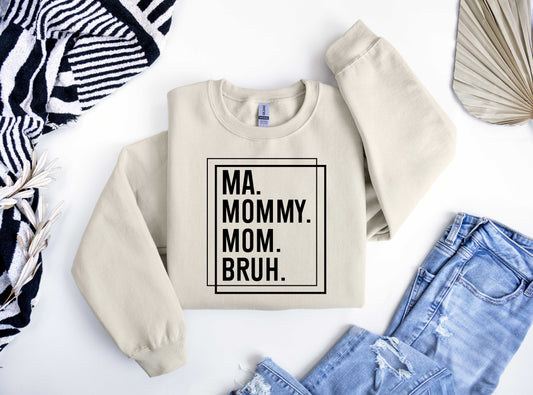 Beige sweatshirt featuring bold black text "MA. MOMMY. MOM. BRUH." inside a double-line square border, perfect for a modern Mother’s Day look.