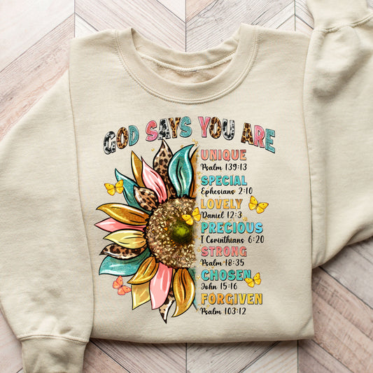 "God Says You Are" DTF transfer design on a beige sweatshirt featuring a vibrant sunflower with faith-based affirmations and Bible verses.