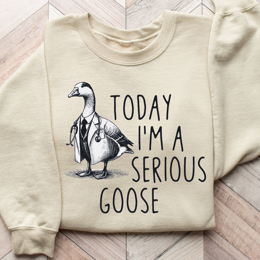 "Today I'm a Serious Goose" DTF transfer design on a beige sweatshirt featuring a detailed illustration of a goose wearing a lab coat and stethoscope with bold text.