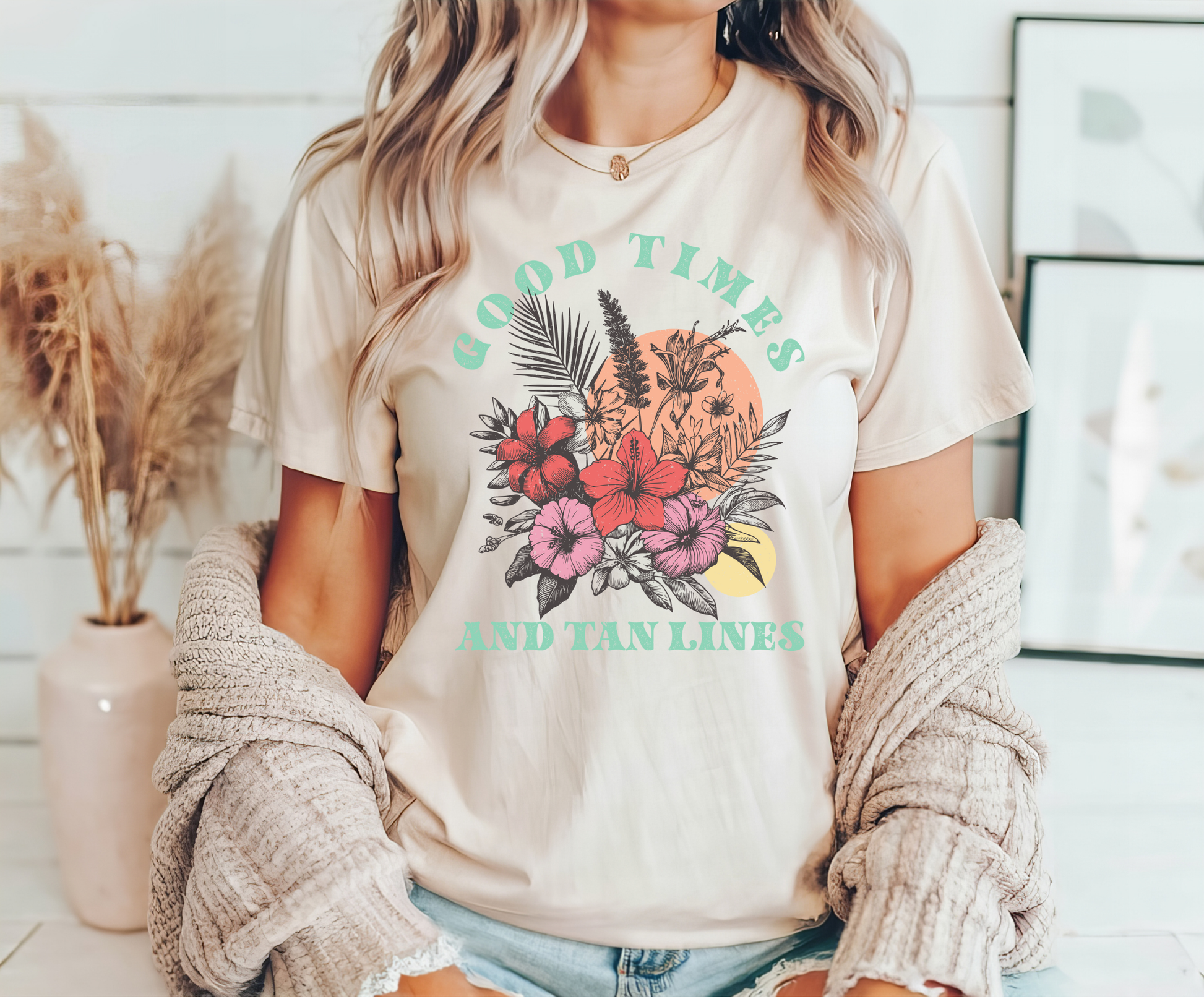 "Good Times and Tan Lines" DTF transfer design on a beige t-shirt featuring tropical flowers, leaves, and a sunset background with summer-themed text.