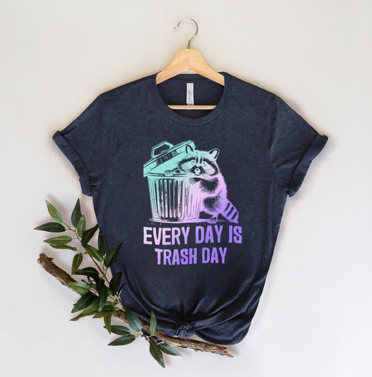 "Every Day is Trash Day" DTF transfer design on a navy t-shirt featuring a raccoon and trash can in pastel hues with funny text.