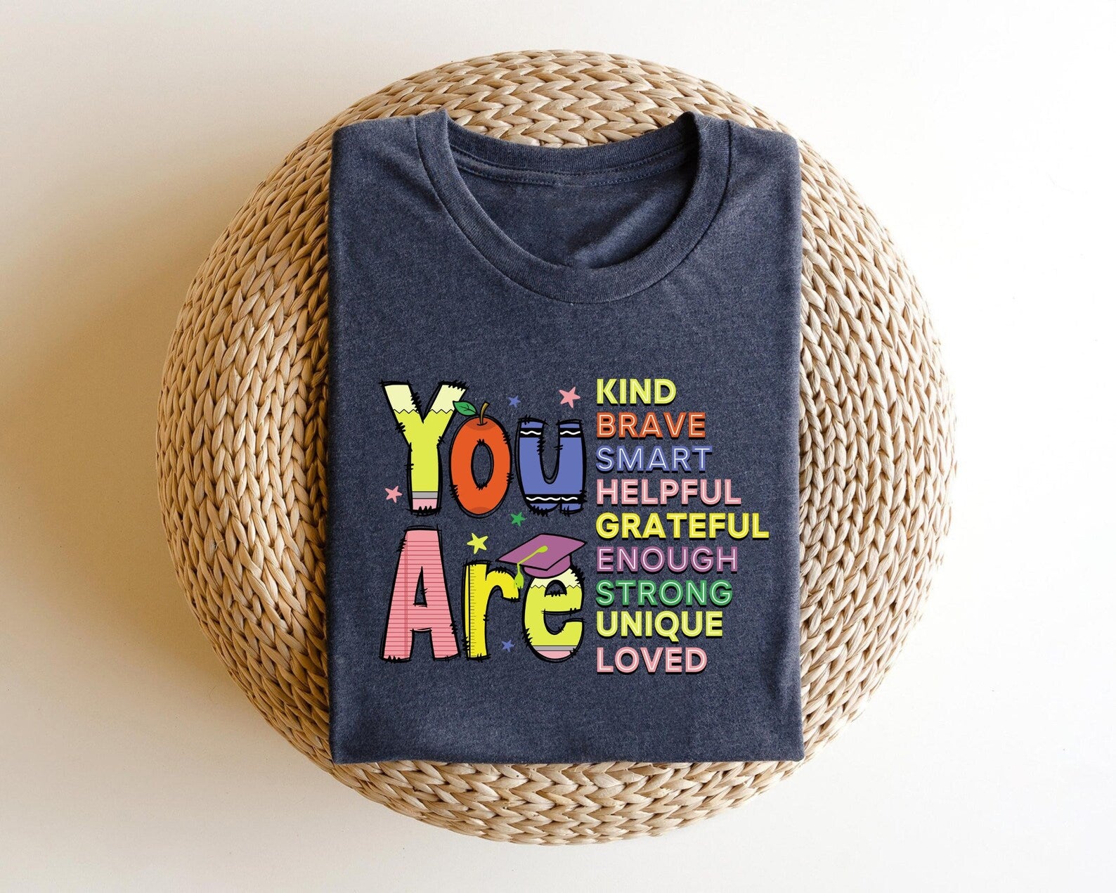 "You Are" DTF transfer design on a navy t-shirt featuring motivational words like "Kind," "Brave," and "Loved" in colorful text with playful accents.