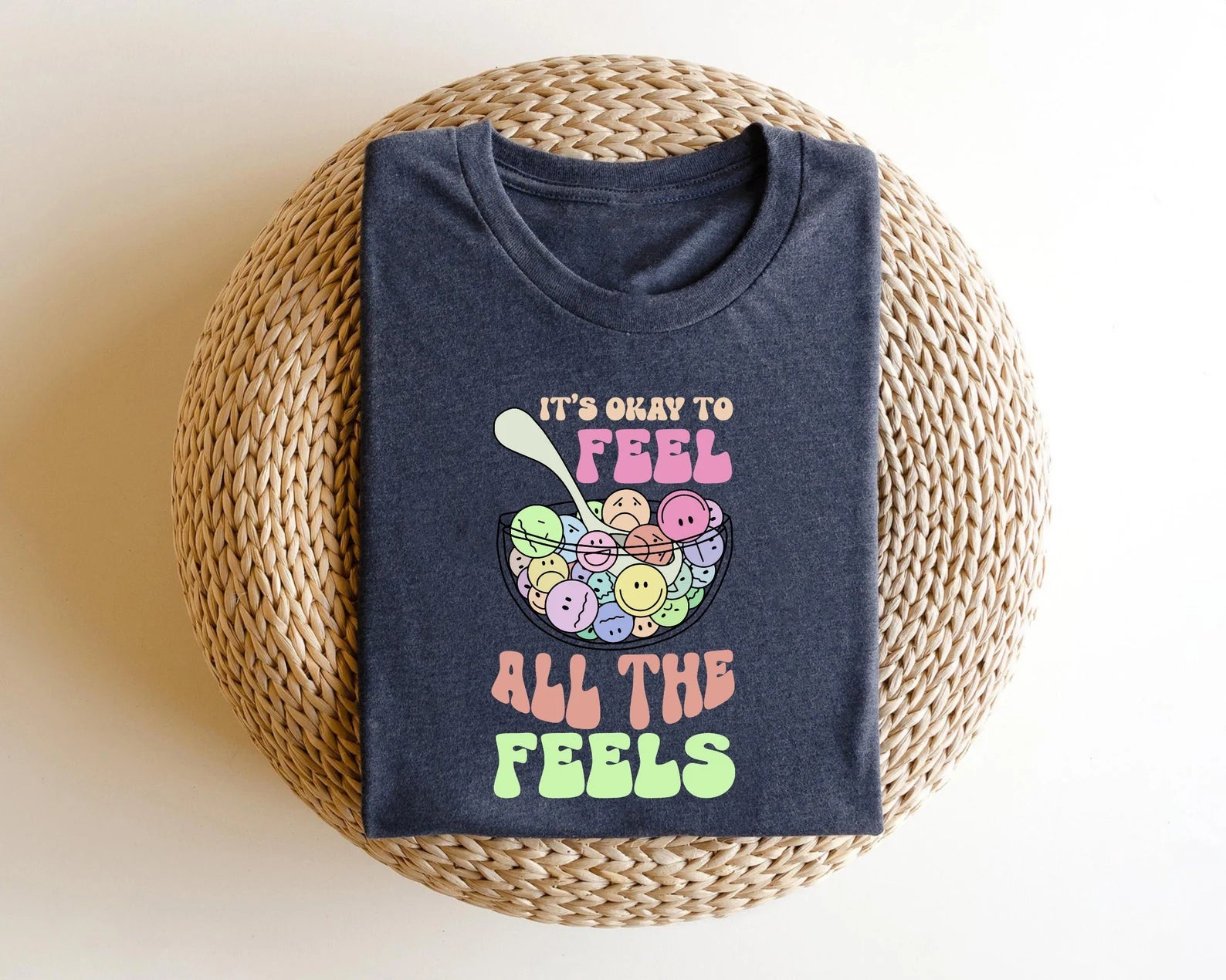 "It's Okay to Feel All the Feels" DTF transfer design on a dark gray t-shirt, featuring colorful smiley faces in a bowl.