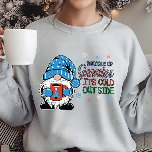 Light gray sweatshirt with “Snuggle Up Gnomies It’s Cold Outside” DTF transfer featuring a cute gnome in a blue hat holding a red mug, surrounded by snowflakes—perfect for cozy winter wear.
