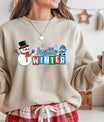 Beige sweatshirt with “Hello Winter” DTF transfer featuring a smiling snowman, blue-hat gnome, and colorful winter lettering—perfect for festive cold-weather apparel.