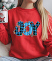 Red sweatshirt with “JOY” DTF transfer featuring blue plaid letters wrapped in colorful Christmas lights—perfect for festive holiday apparel.
