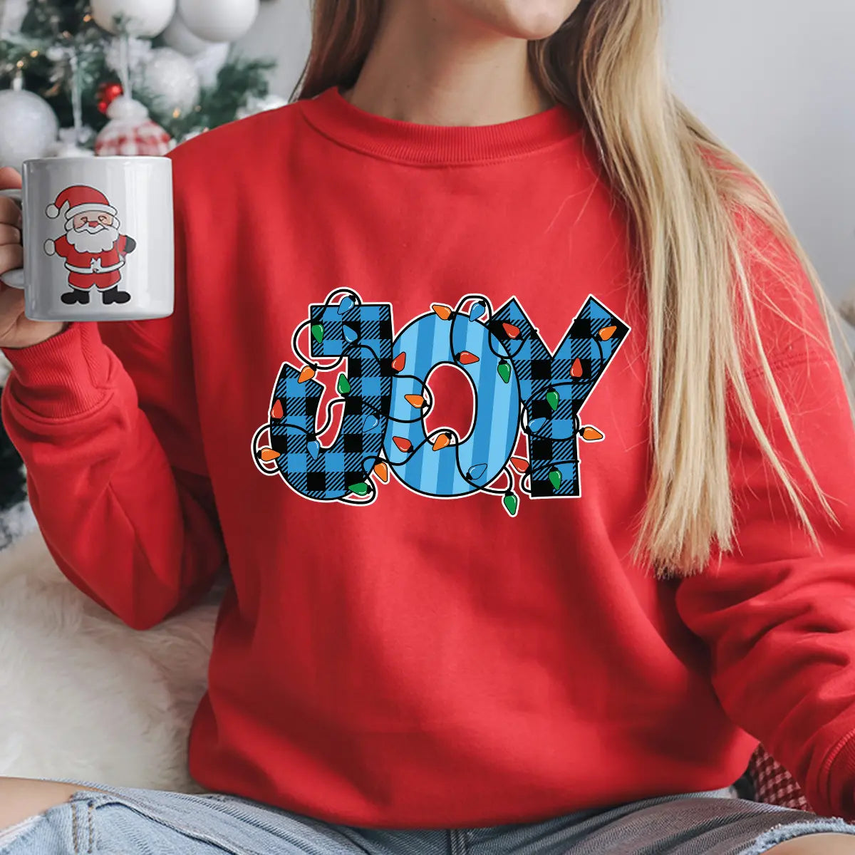 Red sweatshirt with “JOY” DTF transfer featuring blue plaid letters wrapped in colorful Christmas lights—perfect for festive holiday apparel.