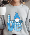 Light gray sweatshirt with “LOVE” DTF transfer featuring a blue-hat gnome holding a snowflake and blue plaid letters—perfect for cozy winter apparel.
