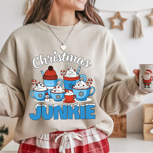 Beige sweatshirt with “Christmas Junkie” DTF transfer featuring holiday mugs with cocoa, whipped cream, and candy canes—perfect for cozy festive apparel.