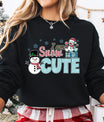Black sweatshirt with “I Am Snow Cute” DTF transfer featuring smiling snowmen, presents, and candy-cane lettering—perfect for festive holiday apparel.