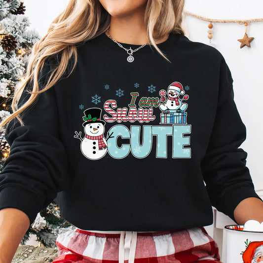 Black sweatshirt with “I Am Snow Cute” DTF transfer featuring smiling snowmen, presents, and candy-cane lettering—perfect for festive holiday apparel.