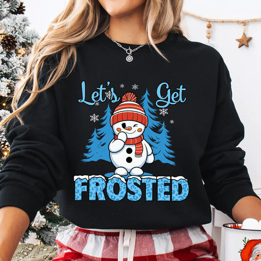 Black sweatshirt with “Let’s Get Frosted” DTF transfer featuring a smiling snowman in a red hat and scarf, blue trees, and icy text—perfect for playful winter apparel.