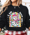 Black sweatshirt with “I Am Snow Cute” DTF transfer featuring a smiling snowman in a pink hat and scarf surrounded by colorful Christmas lights—perfect for festive winter apparel.