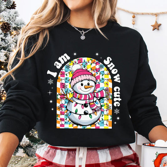 Black sweatshirt with “I Am Snow Cute” DTF transfer featuring a smiling snowman in a pink hat and scarf surrounded by colorful Christmas lights—perfect for festive winter apparel.