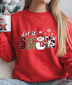 Red sweatshirt with “Let It Snow” DTF transfer featuring a snowman in a red hat, plaid, leopard, and cow print letters—perfect for trendy holiday apparel.