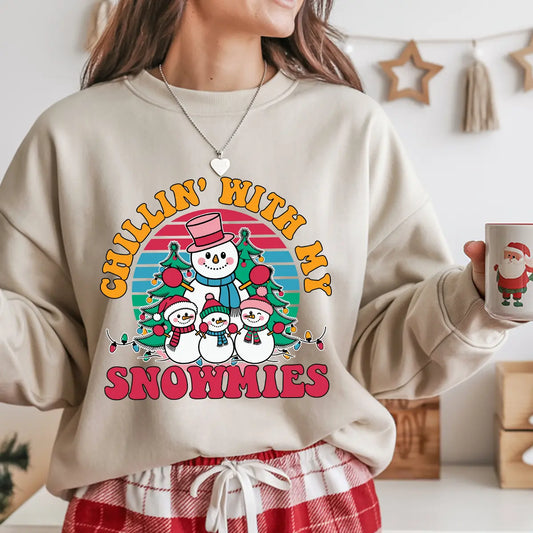 Beige sweatshirt with colorful retro “Chillin’ With My Snowmies” DTF transfer design featuring a happy snowman family in front of a striped sunset background.