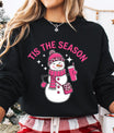 Black sweatshirt with pink “Tis the Season” DTF transfer featuring a fashionable snowman in pink leopard-print hat and scarf holding a drink cup.