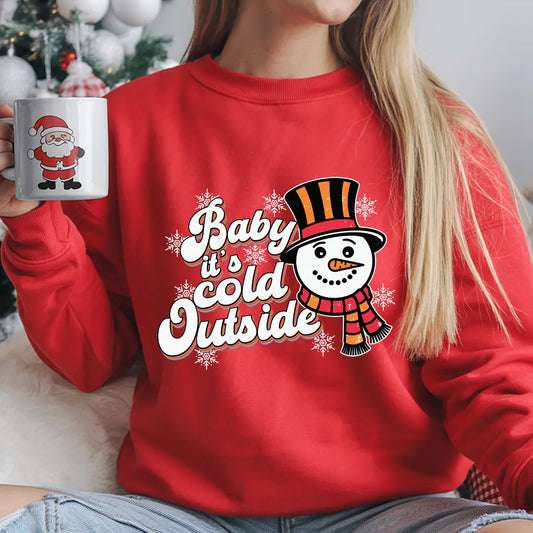 Red sweatshirt with “Baby It’s Cold Outside” DTF transfer featuring a retro snowman in an orange-and-black hat and striped scarf with snowflakes.