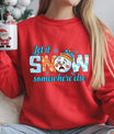 Red sweatshirt with a cartoon snowman and the text “Let It Snow Somewhere Else” in blue and orange winter-themed letters.