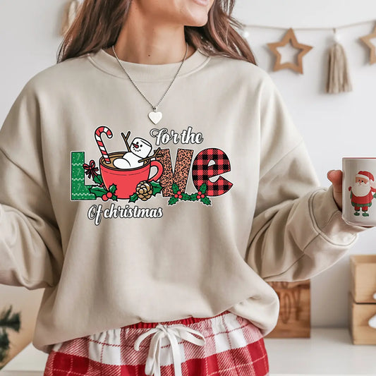 Beige sweatshirt with “For the Love of Christmas” design featuring a snowman in a red mug with candy cane, plaid letters, and festive holly decorations.