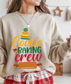 Beige sweatshirt with colorful “Cookie Baking Crew” text, winter hat, and rolling pin graphic, perfect for holiday baking enthusiasts.