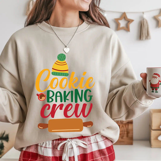 Beige sweatshirt with colorful “Cookie Baking Crew” text, winter hat, and rolling pin graphic, perfect for holiday baking enthusiasts.