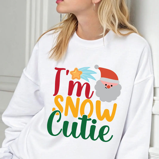 White sweatshirt with “I’m Snow Cutie” text, Santa face, and shooting star graphic — festive Christmas sweatshirt.